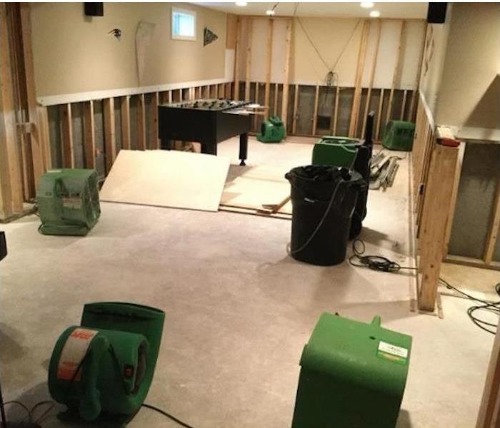 carpet removed, lower wall panels removed, studs showing, equipment drying out the room
